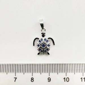 Vue détaillée du pendentif tortue en argent avec gemme bleue et mesure à la règle