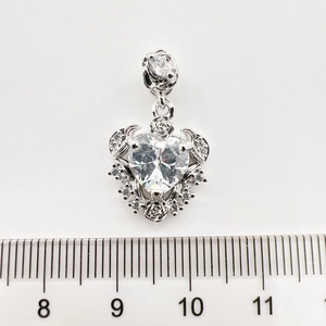 Gros plan sur pendentif cœur argenté avec zircone et roses 3D sur fond blanc brillant