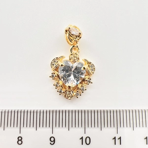 Gros plan du pendentif cœur doré avec cristal, détails de rose et règle de mesure