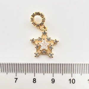 Détail d'un pendentif étoile doré avec zircons et échelle de mesure de 1,5 cm