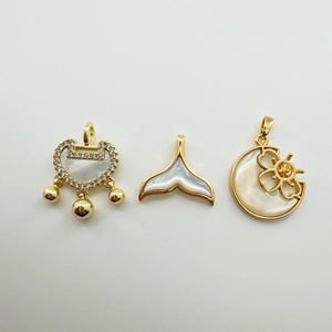 Detalle de dijes bañados en oro de 18K con nácar natural en forma de candado y cola de pez