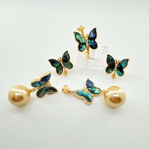 Detail view of gold-plated butterfly jewelry set with iridescent wings and golden pearls