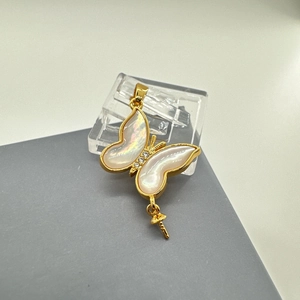 Macro detail of gold-plated butterfly pendant with iridescent shell inlay and zircons