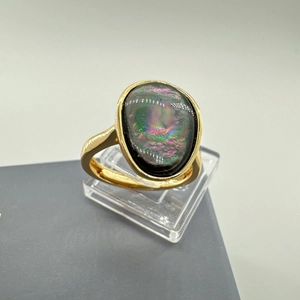 Dettaglio macro di un anello in oro 18 carati con una grande madreperla nera ovale iridescente