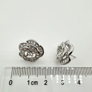 Detailed view of silver camellia earrings with cubic zirconia and measuring scale