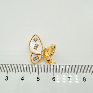 Macro detail of butterfly pendant with white shell wings and zircon on scale ruler