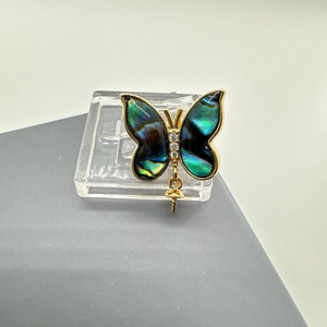 Macro detail of butterfly jewelry pendant with gold plating and iridescent abalone shell wings