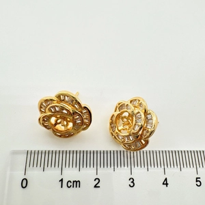 Macro shot of 925 silver camellia earrings with shell inlay next to a measuring scale