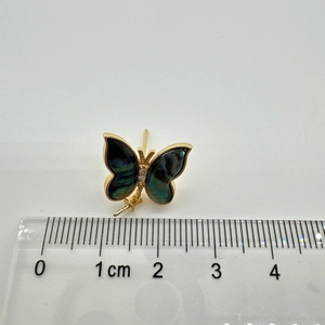 Macro detail of butterfly earring with gold plating and iridescent dark shell inlay