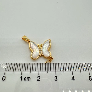 Macro detail of gold-plated butterfly pendant with mother of pearl and crystal inlay