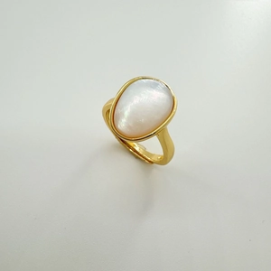 Dettaglio anello dorato regolabile con grande inserto in madreperla bianca ovale
