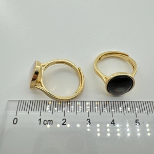 Dettaglio di anelli regolabili placcati oro con pietre di conchiglia bianche e nere