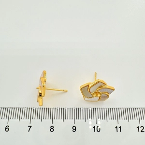 Dettaglio di orecchini a fiore in argento 925 con petali di conchiglia bianca e righello
