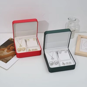 Dettaglio di scatole regalo rosse e verdi con collana e orecchini a quadrifoglio e perle