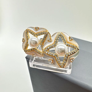 Dettaglio di orecchini stella in madreperla con perle e argento 925 dorato