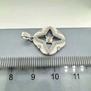 Dettaglio del ciondolo in argento Stella Polare con conchiglia accanto a un righello