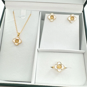 Detail view of gold-plated four-leaf clover jewelry set with white shell inlay in a gift box