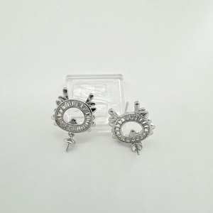 Detalle macro de pendientes plateados con circonitas y diseño decorativo de asta de ciervo