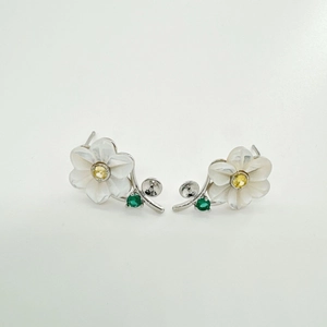 Detailed macro of s925 silver daisy earrings with white shell petals and green gems