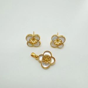 Detailed macro view of gold-plated four-leaf clover jewelry set with white shell inlay