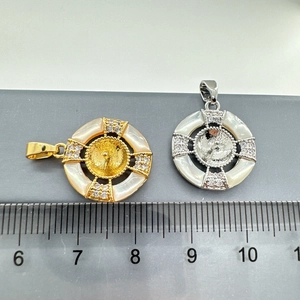 Detailed view of silver and gold shell pendants with zirconia showing 1.5cm measurement