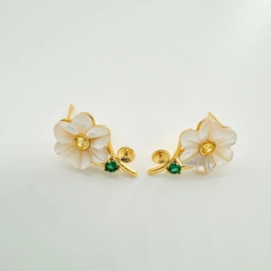Macro shot of flower earrings with white shell petals and a yellow center gemstone
