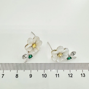 Macro view of floral S925 silver earring studs with shell petals and yellow zircons