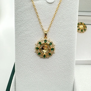 Dettaglio di un set di gioielli vintage dorati con pietre verdi e zirconi chiari