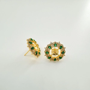 Dettaglio degli orecchini a fiore dorati con pietre marquise verdi e perni in argento