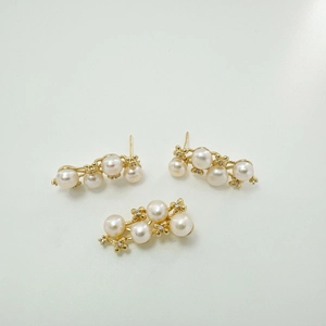 Macro detail of elegant cream pearl earrings with gold accents and sparkling zircon stones