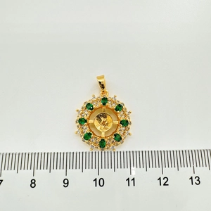 Dettaglio macro di un ciondolo a fiore dorato con pietre verdi e rilievo religioso