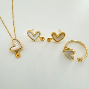 Dettaglio macro di set gioielli a cuore in madreperla dorata 18k con basi per il fai da te