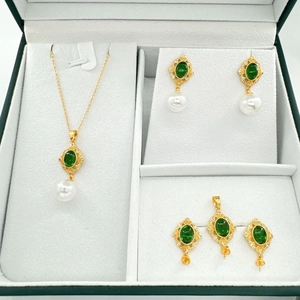 Vintage gold necklace and pearl earrings set with emerald green stones in a display box
