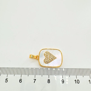 Détail macro du pendentif en nacre plaqué or 18K avec zircon de cœur et échelle 1,8cm