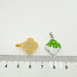 Detailed view of 18K gold-plated clover charms with ruler for size reference