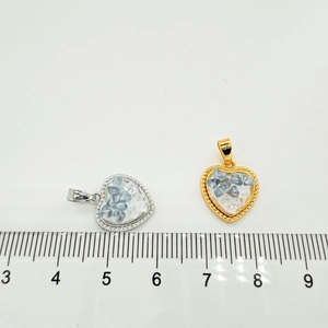 Detail view of heart pendants with natural crystals and gold frame next to a ruler