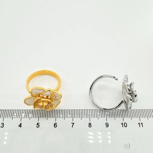 Detail van bloemvormige 18K gouden en zilveren ringen met wit emaille en zirkonia's