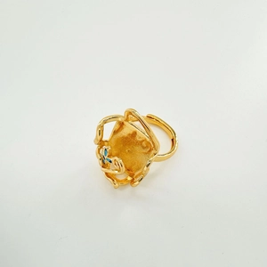 Detail van de 18K vergulde ring met vierkante gehamerde textuur en blauwe bloemversieringen