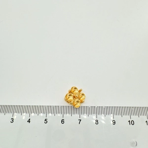 Makroaufnahme von 10mm Kleeblatt-Anhängerfassung in Gold mit Lineal zur Größenmessung