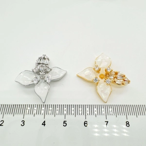 Macro detail of a 2.5cm 18K gold floral pendant with white petals and sparkling zircons