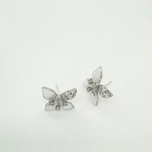 Macro view of butterfly earrings with white enamel wings and sparkling zircon inlay