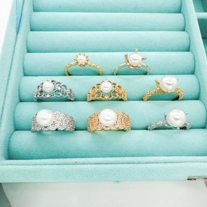 Collection of 18k gold plated lace pearl rings in a blue velvet jewelry display box