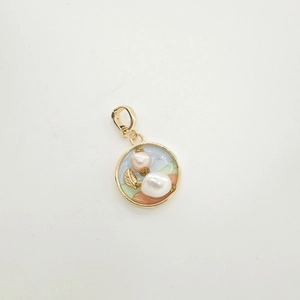 Floral enamel pendant with baroque pearls and gold leaves on a white background