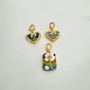 Detail of 18K gold enamel heart pendants with inlay pearls and floral patterns