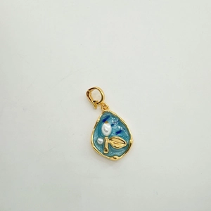 Detailed macro view of sky blue enamel pearl pendant with gold leaf motif clasp