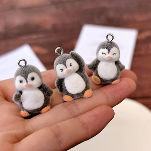Drie schattige gevlokte pinguïnhangers met metalen ringen, in de hand gehouden