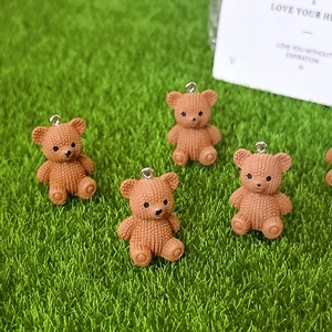 Brown resin bear pendants with knit texture and silver loops on green grass