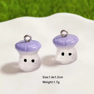 Macro detail of two purple resin mushroom charms with silver rings on a tray