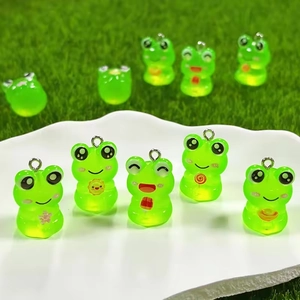 Luminous resin frog charms with diverse belly patterns and silver rings on green grass