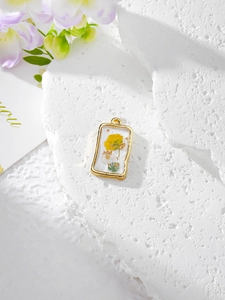 Close-up of a gold rectangular resin pendant with a yellow flower and gold foil flakes